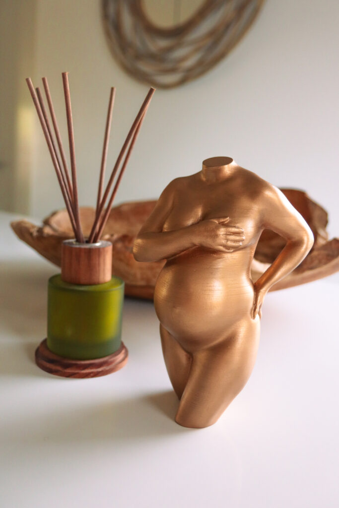 Sculptuur van een zwangere buik, met een simplistische stijl die de essentie van het moederschap benadrukt.